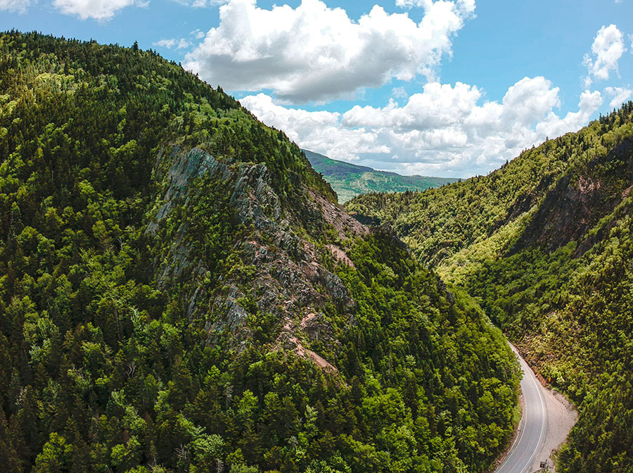 aerial view of a road cutting through green mountains