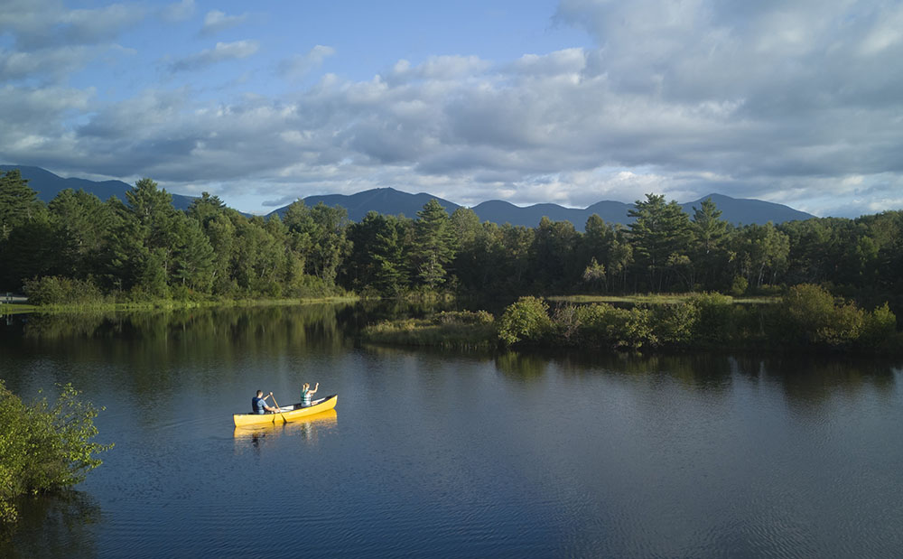people canoeing in a lake with mountains in background