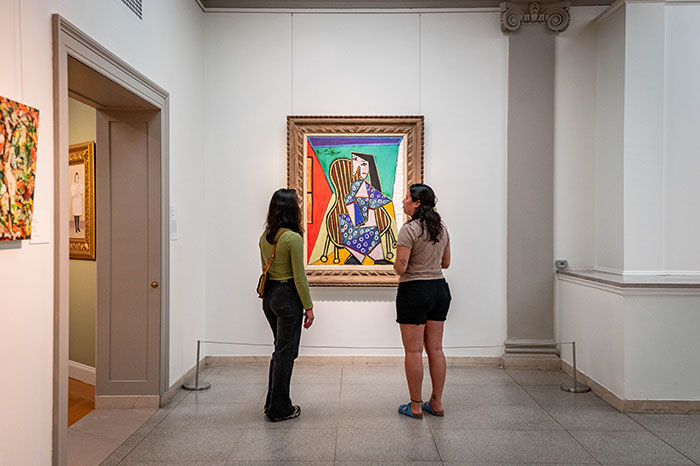 two women looking at a painting in a museum