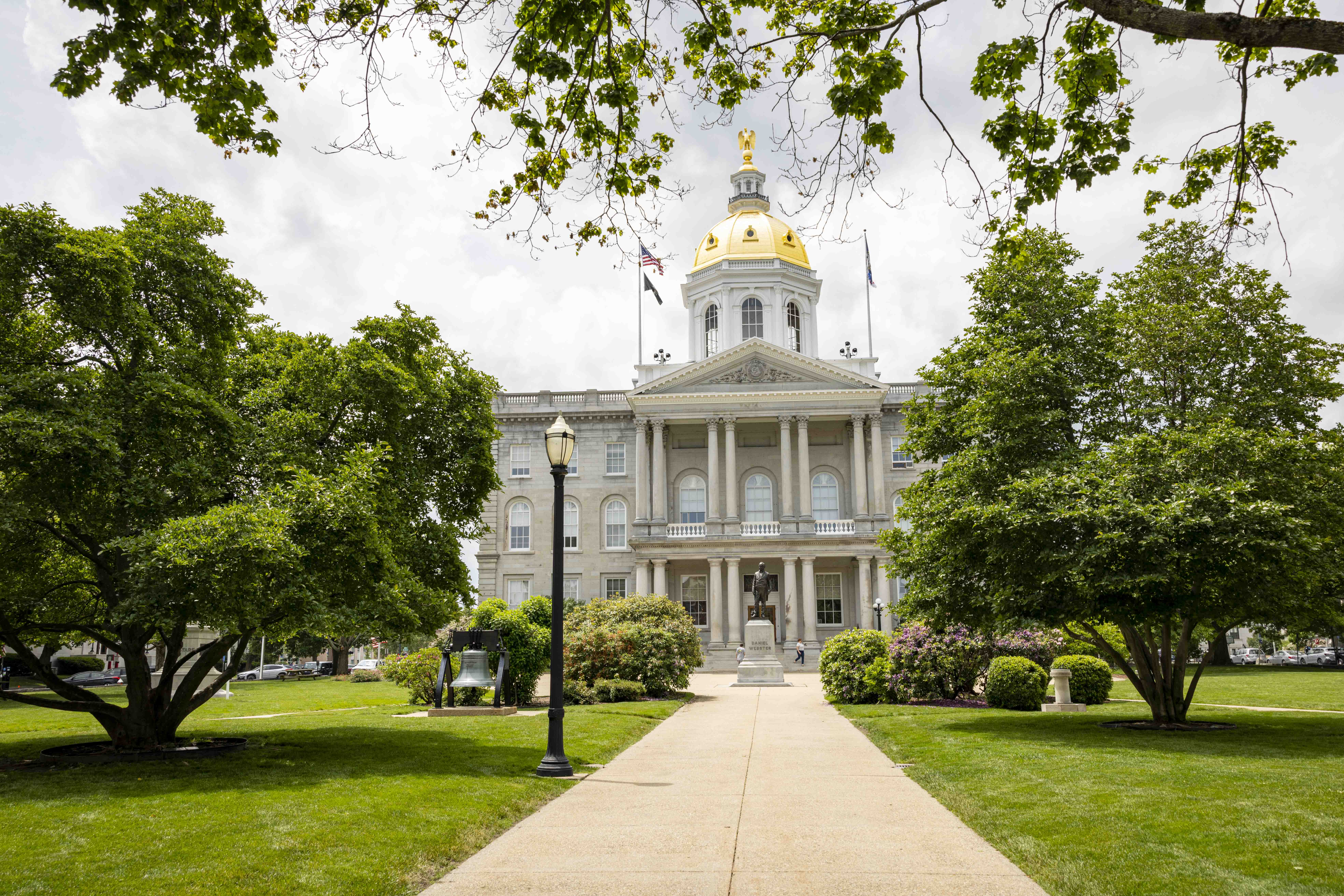 the NH statehouse with green lawn and trees surrounding