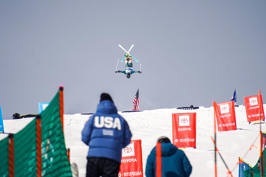 a view of a ski race course, with a crowd wearing "USA" jackets gathered at the bottom.