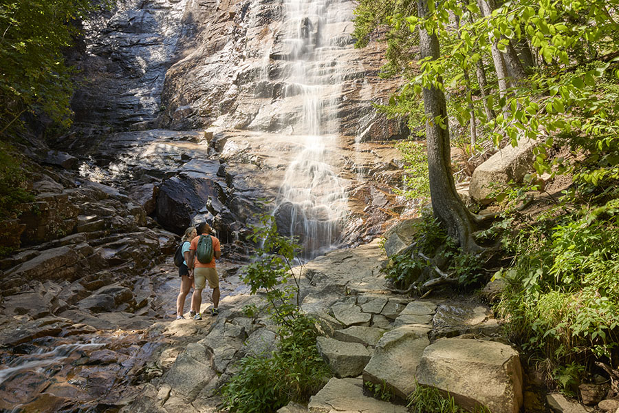 a man and woman looking up at a waterfall