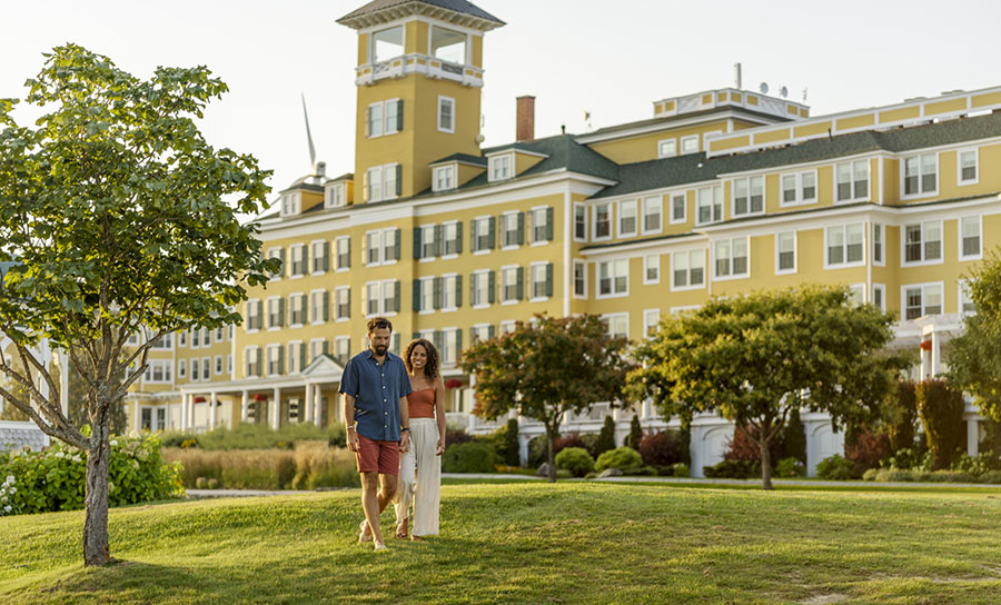 a couple walking in front of yellow hotel