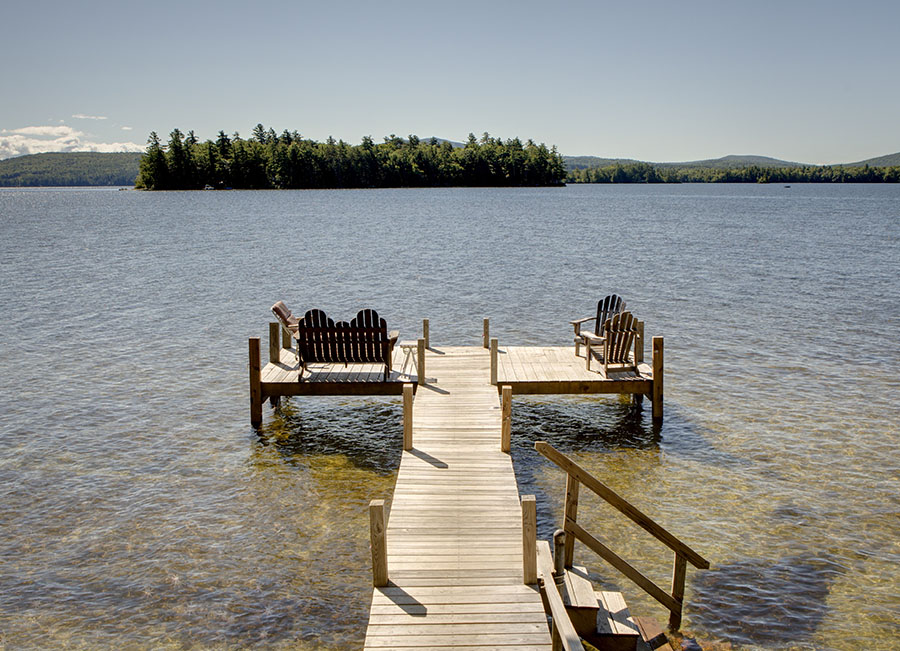 a dock reaching out into a lake with chairs on it