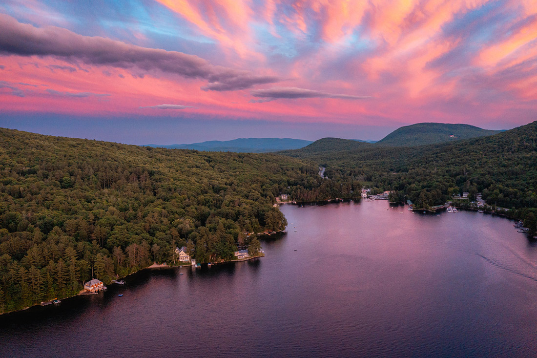 an aerial view of a lake and mountains at sunset