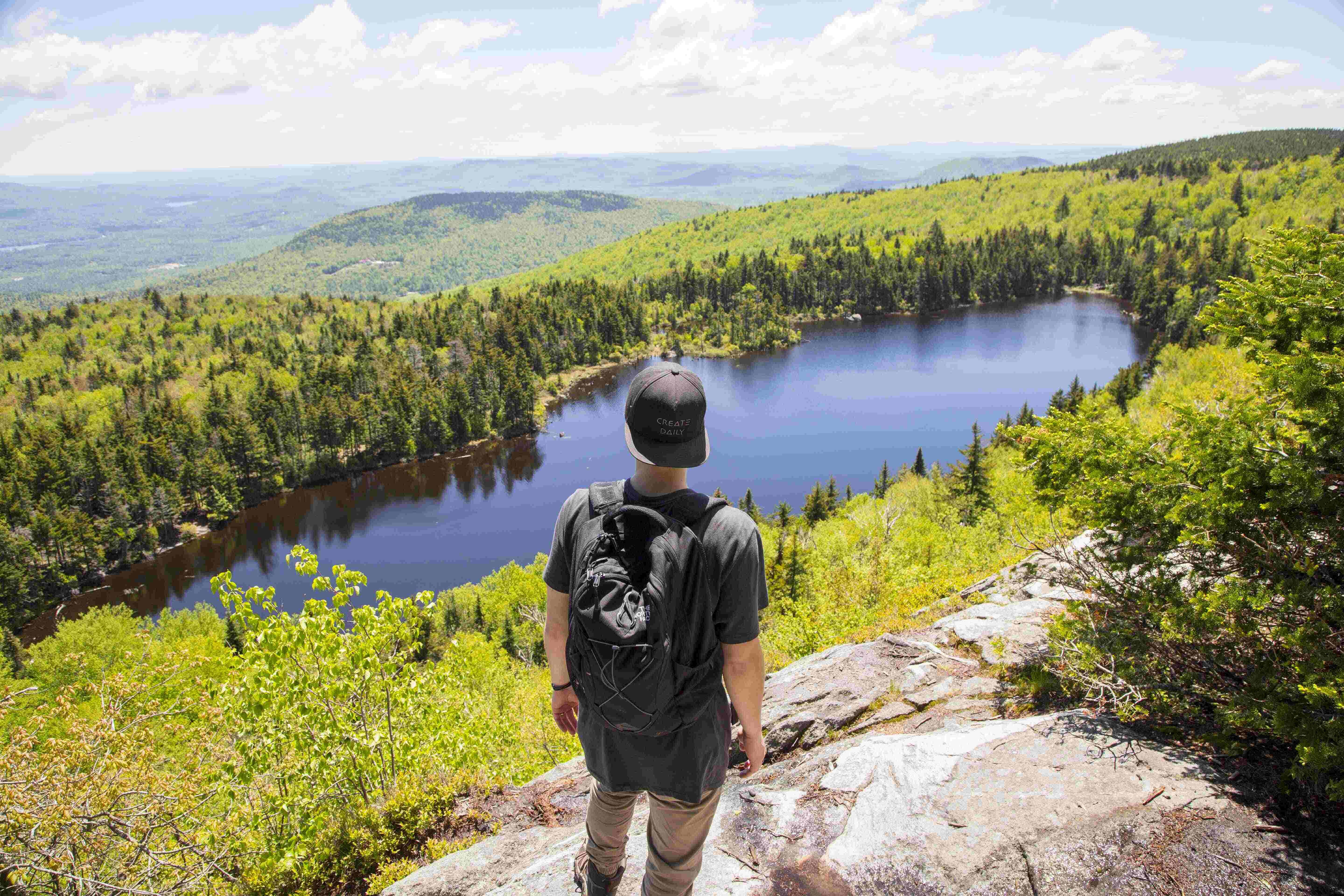 a hiker looking at a view of a lake with a backpack on